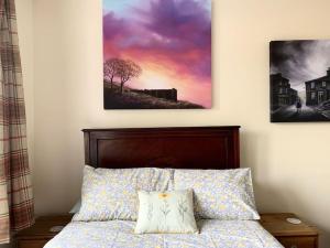 a bedroom with a bed with two paintings on the wall at Artist Hideaway Main Street Haworth in Haworth