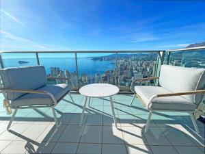 einen Balkon mit 2 Stühlen, einem Tisch und Aussicht in der Unterkunft Gran lujo, terraza grande y vistas al mar - planta 41 in Benidorm