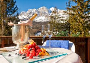 a table with a bottle of champagne and a plate of strawberries at Boutique Hotel Villa Blu Cortina D'Ampezzo in Cortina dʼAmpezzo