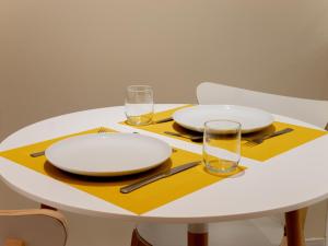 une table blanche avec des assiettes et des verres sur une serviette jaune dans l'établissement Le Lion - Plain-pied, WIFI, YT Premium - 2RFHomes, à Château-Thierry