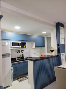 a kitchen with blue cabinets and a white refrigerator at Apartamento Condomínio Lençóis Confort in Barreirinhas