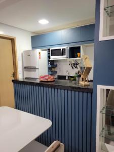 a kitchen with a counter with a microwave and refrigerator at Apartamento Condomínio Lençóis Confort in Barreirinhas