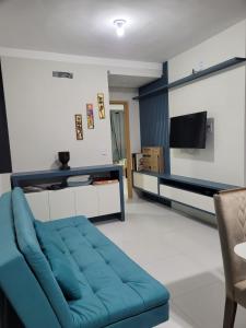 sala de estar con sofá azul y TV en Apartamento Condomínio Lençóis Confort, en Barreirinhas