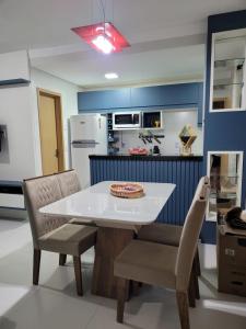- une cuisine avec une table et des chaises blanches dans l'établissement Apartamento Condomínio Lençóis Confort, à Barreirinhas