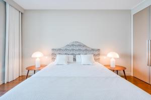 a white bedroom with a large white bed with two lamps at Suite 107 - Two bedroom apartment in Funchal