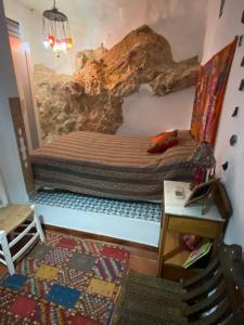 a bed in a room with a cave wall at Casa La Maquica in Campo de Criptana