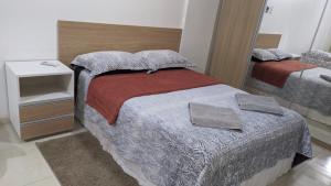 Dormitorio pequeño con cama y espejo en Flat Mobiliado na Ponta Verde, en Maceió