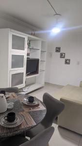 uma sala de estar com uma mesa e cadeiras e uma televisão em Flat Mobiliado na Ponta Verde em Maceió