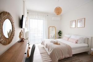 a white bedroom with a bed and a mirror at La Petite Fleur Studio in Xylokastro