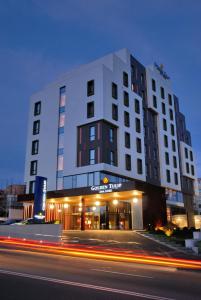 a tall white building with a street in front of it at Golden Tulip Ana Dome Hotel in Cluj-Napoca