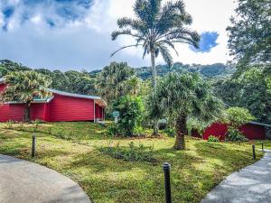 una casa roja con palmeras delante en Cloud Forest Lodge by Böëna, en Monteverde