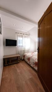 a bedroom with a bed and a table and a television at L'Escapade Citadine in Bischheim