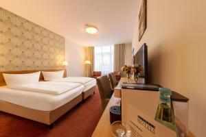 una habitación de hotel con 2 camas y una mesa con flores en Michels Thalasso Hotel Nordseehaus, en Norderney