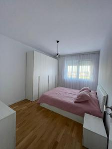a white bedroom with a bed and a window at Lovely apartment in Peja Citycenter in Peje