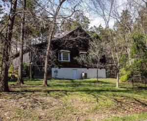 a black house with a white garage and trees at Cozy Cabin w/ Indoor Fireplace & Tranquil views in Luray