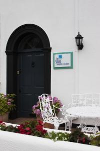 um par de cadeiras brancas sentadas em frente a uma porta em The Townhouse Strand em Dunmore East