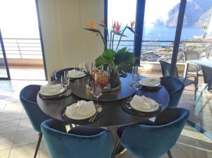 een tafel met stoelen en borden en wijnglazen bij Luxury Los Gigantes Apartment in Puerto de Santiago