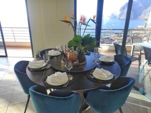 una mesa con sillas, platos y copas de vino en Luxury Los Gigantes Apartment, en Puerto de Santiago