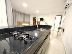 a kitchen with a black counter top with a stove at Flats Paraíso Louveny in Japaratinga