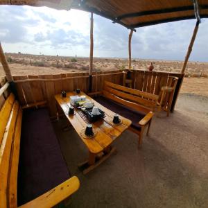 einem Holztisch und Bänken vor einem Feld in der Unterkunft The Red House in Amboseli-Nationalpark