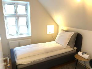 a small bed in a room with a window at Huset ved springvandet in Randers