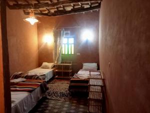 una camera con due letti e una finestra di auberge restau tombouctou a Aït Ben Haddou