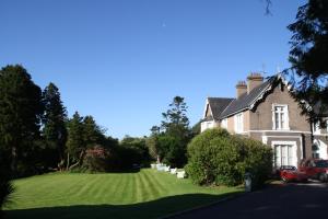 a house with a large lawn and trees at Maranatha Country House in Blarney
