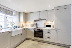 a white kitchen with white cabinets and a window at The Mustard Pot - Kirkby Lonsdale in Kirkby Lonsdale