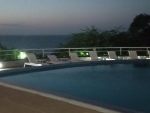 Catia La Mar的住宿－Airport BleuSuite Apartment，游泳池配有椅子,晚上则享有海景