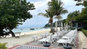 eine Reihe weißer Stühle am Strand in der Unterkunft Bella Vista Beach Resort Koh Lipe in Ko Lipe