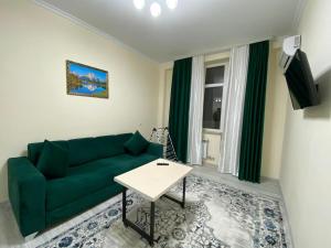 a living room with a green couch and a table at Rusel Hotel in Aktau