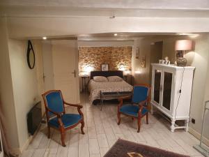 a bedroom with a bed and two blue chairs at la Villa Mancelle in Le Mans