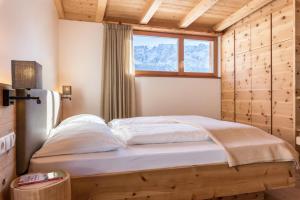 - une chambre avec un lit dans une pièce dotée d'une fenêtre dans l'établissement Villa Solinda App Rossini, à Selva di Val Gardena