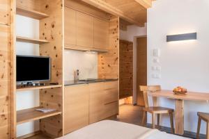a kitchen with wooden cabinets and a tv and a table at Villa Solinda App Rossini in Selva di Val Gardena