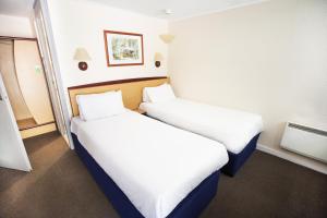 two beds in a hotel room with white sheets at Campanile Hotel Runcorn in Runcorn