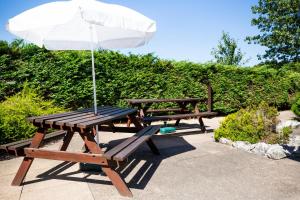 a picnic table with an umbrella and two benches at Campanile Hotel Runcorn in Runcorn