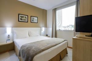 a hotel room with a bed and a flat screen tv at Interclass Florianópolis in Florianópolis