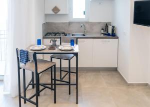 cocina con mesa, 2 sillas y lavamanos en Alloggio nuovissimo al centro e rilassante, en Isquia