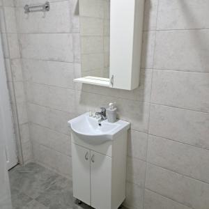 bagno bianco con lavandino e specchio di LIBERO APARTMANI a Surčin