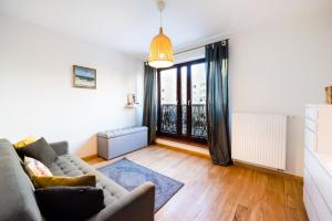 ein Wohnzimmer mit einem Sofa und einem großen Fenster in der Unterkunft Bemowo Green Wood Apartment in Warschau