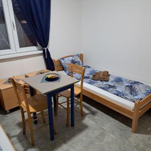 a small room with a bed and a table and chairs at LIBERO APARTMANI in Surčin