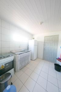 a kitchen with white tile floors and white appliances at BRUNO KLEMTZ DK4 CASA PISCINA CHURRASQUEIRA SINUCA 3 AR WIFI 3 VaGAS 3 DORM in Itapema