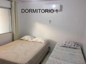 2 camas en una habitación con un cartel en la pared en BRUNO KLEMTZ DK4 CASA PISCINA CHURRASQUEIRA SINUCA 3 AR WIFI 3 VaGAS 3 DORM, en Itapema