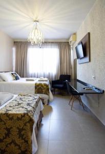um quarto de hotel com duas camas e um lustre em HOTEL PIACENTINI em Campo Mourão
