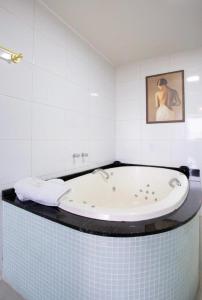 uma casa de banho com uma banheira com um quadro na parede em HOTEL PIACENTINI em Campo Mourão