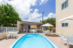 a swimming pool with chairs and a table and an umbrella at Ocean Residence in Porto De Galinhas