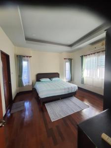 ein Schlafzimmer mit einem Bett sowie Holzböden und -fenster in der Unterkunft Maerim​ relax in Mae Rim