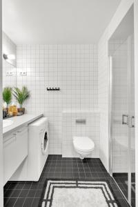 a white bathroom with a toilet and a sink at Tjuvholmen II, As Home in Oslo