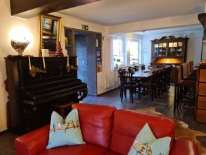 a living room with a red couch and a piano at Pilgrims Gästeapartements in Meschede