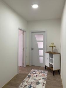 a white room with a table and a lamp on a desk at White Apartments in Kosovo Polje